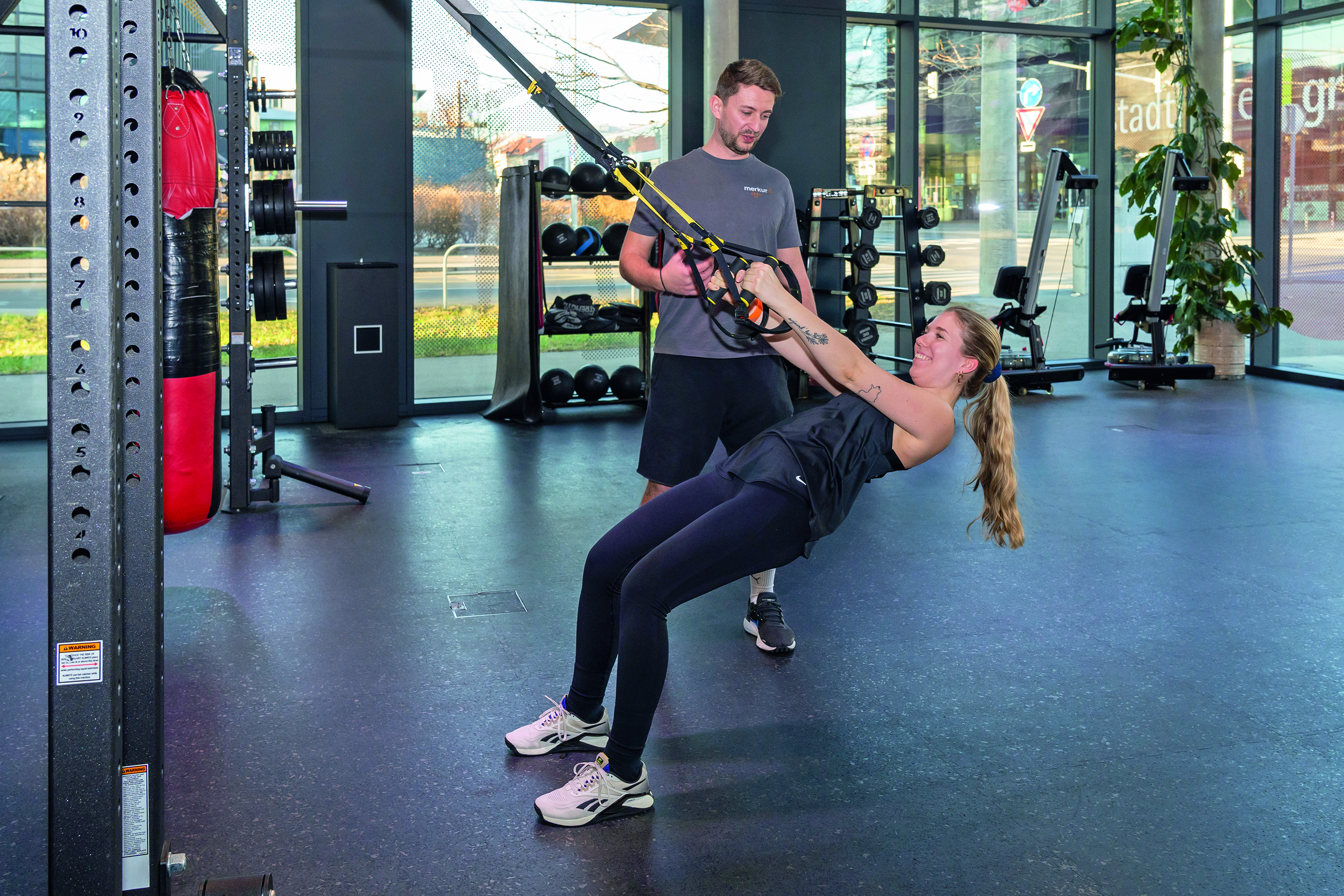 Frau trainiert mit Trainer im Fitnessstudio