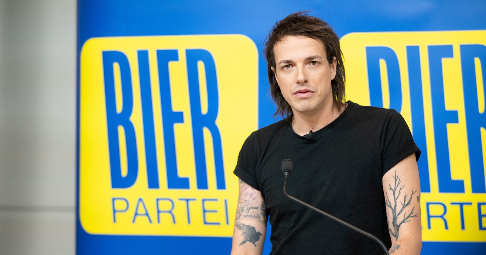 Bierpartei-Gründer Dominik Wlazny alias Pogo vor dem blau-gelben Logo der Partei.