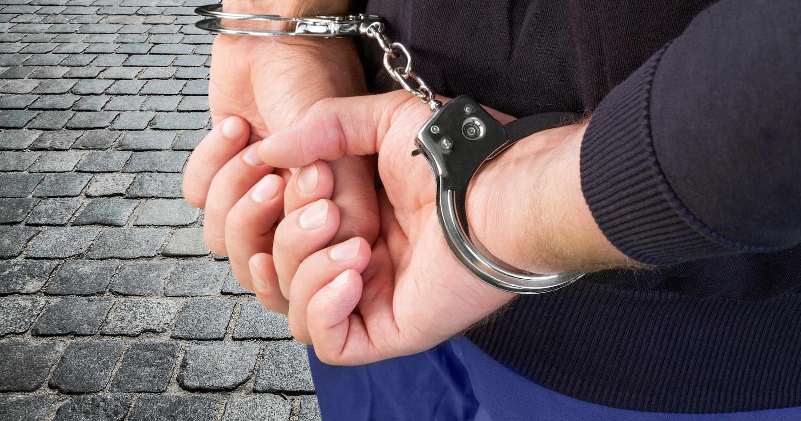 Ein junger Mann in Handschellen.