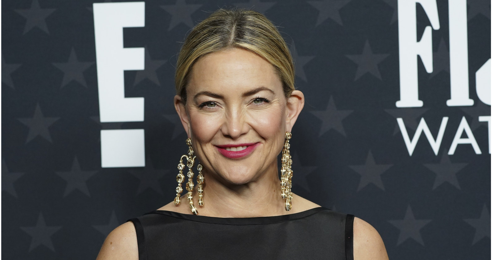 Blonde Frau in schwarzem Kleid lächelt in die Kamera