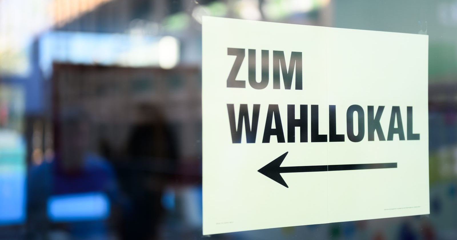 Schild mit Pfeil und Text &quot;Zum Wahllokal&quot;.