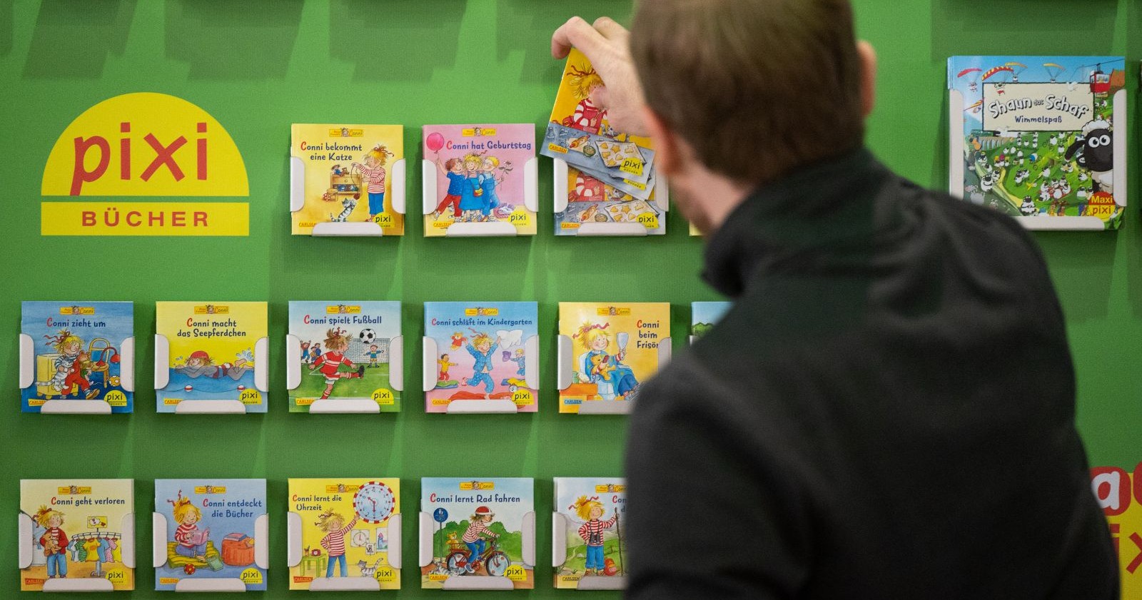 Ein Mann vor einem Pixi-Regal.