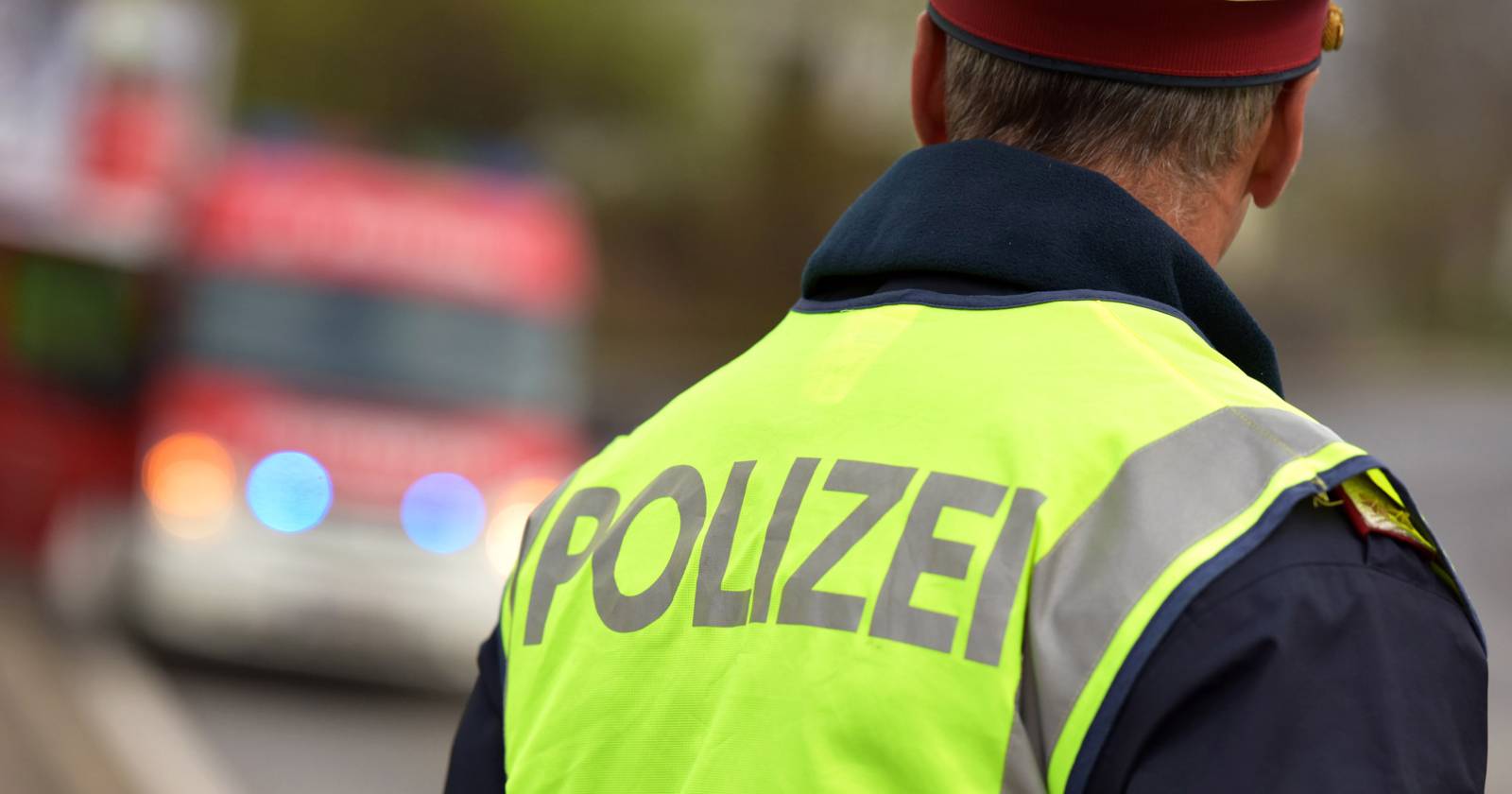 Rückenansicht eines Polizeibeamten, der eine gelbe Warnweste trägt