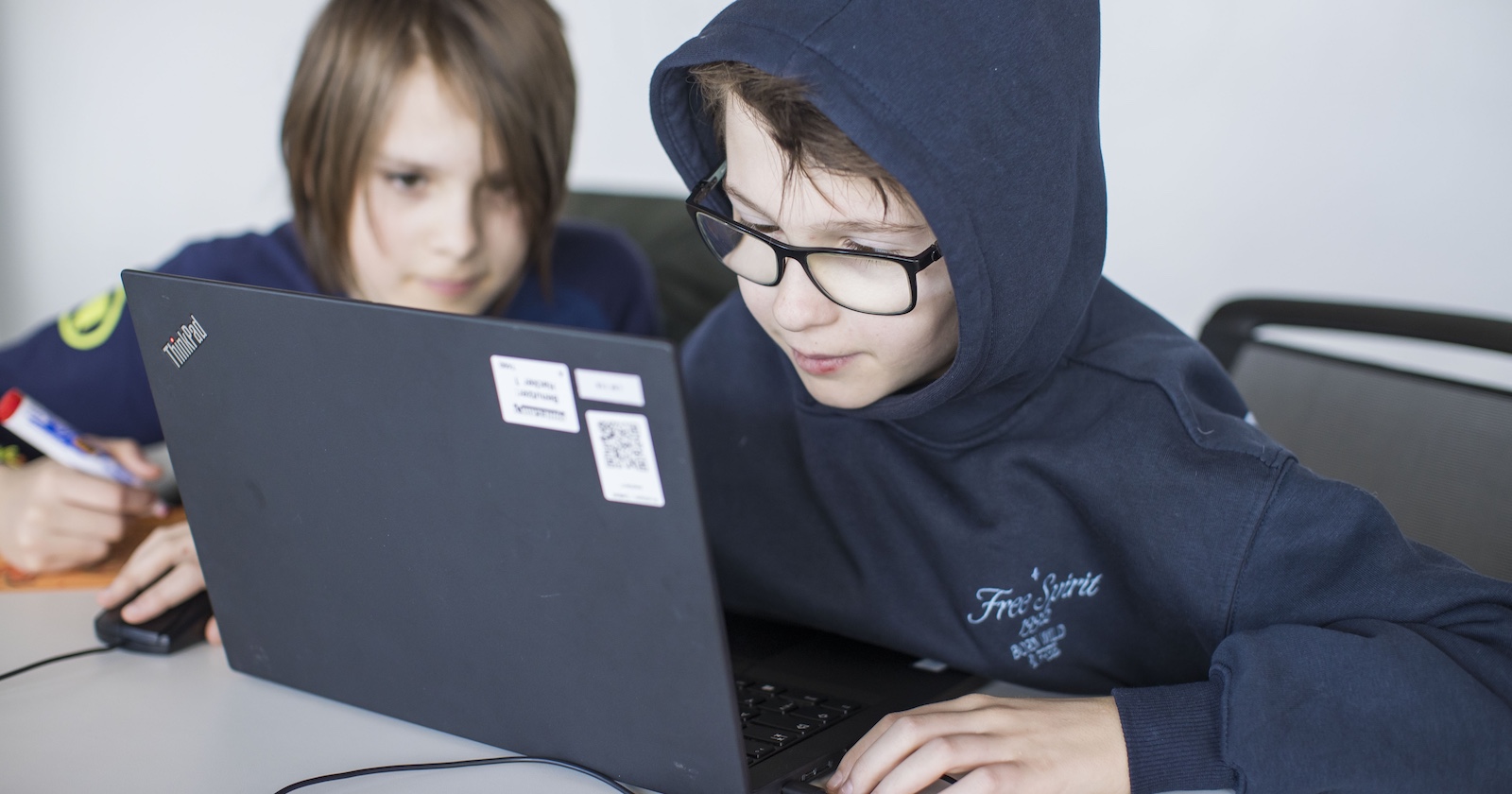 Zwei Kinder sitzen gespannt vor einem Laptop.