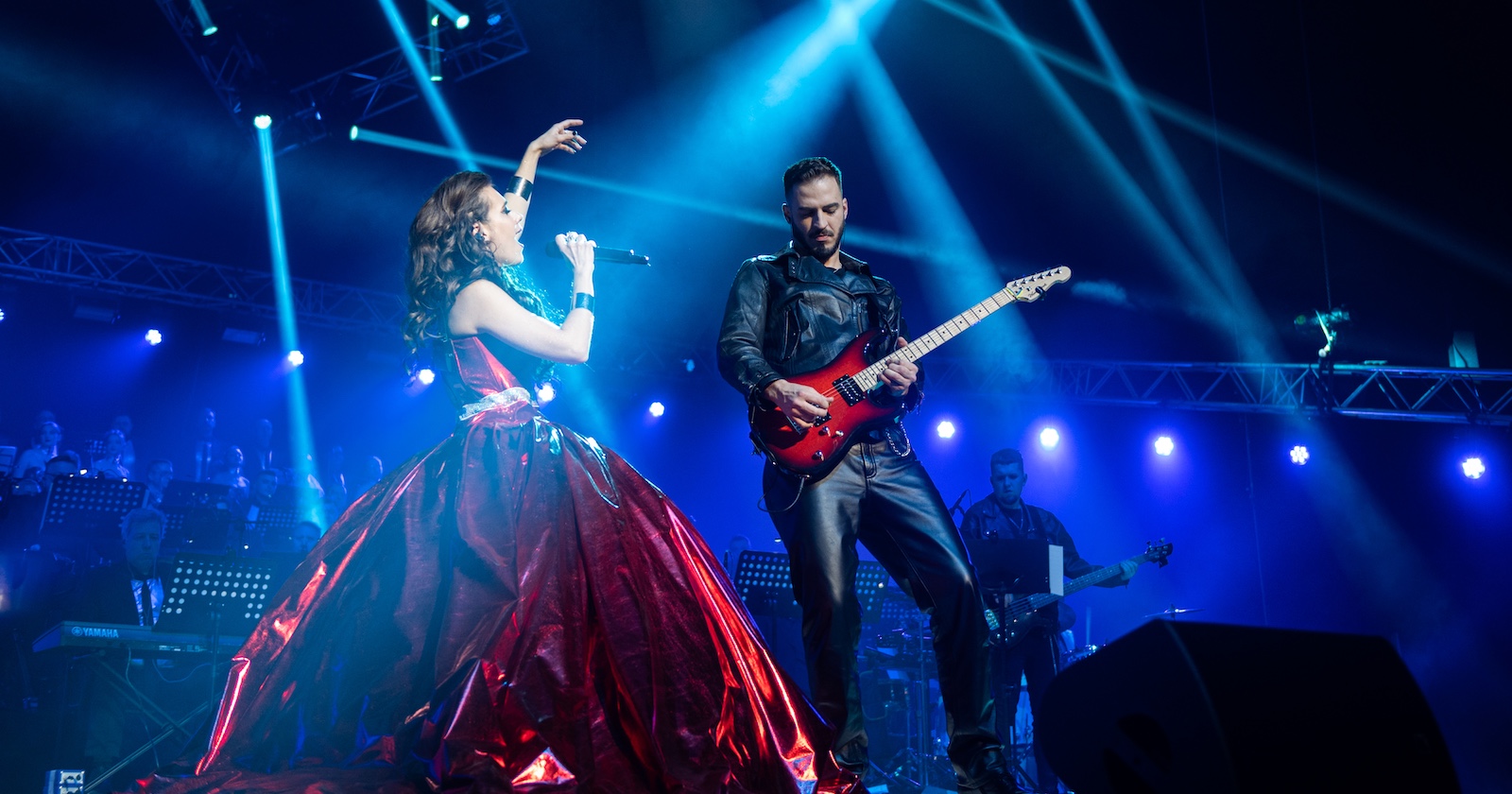 Sängerin in großer roter Robe und Gitarrist in Leder auf der Bühne