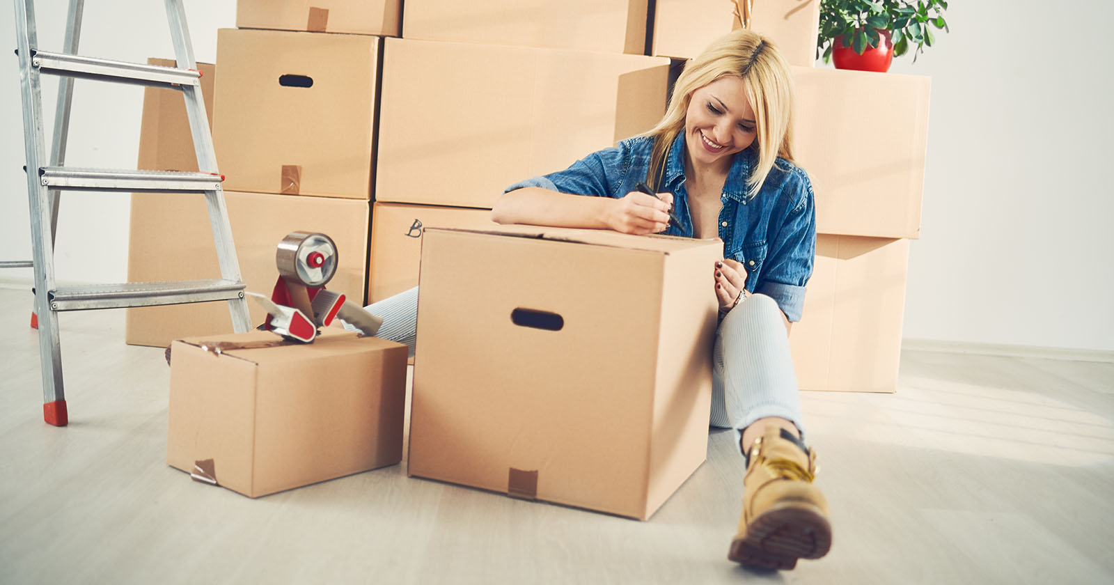 Frau sitzt am Boden mit Umzugskartons | Credit: iStock.com/millann