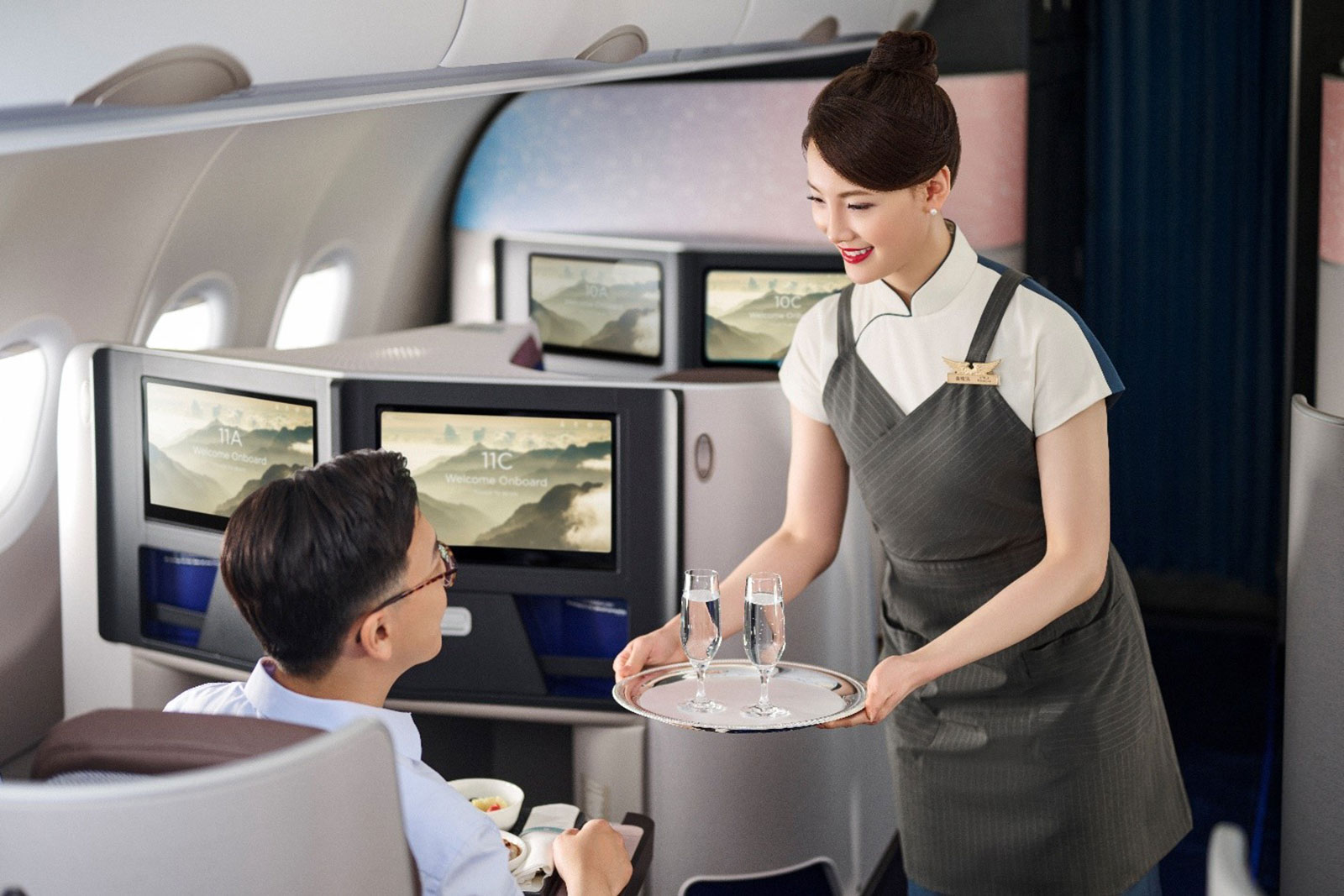 Stewardess serviert männlichem Fluggast Getränke auf dem Tablett | Credit: China Airlines