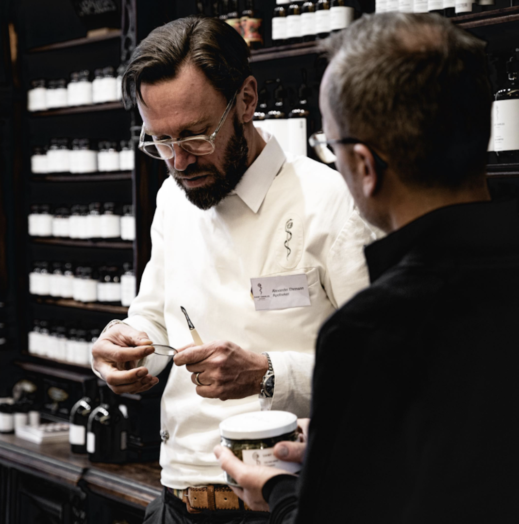 Porträt eines Mannes in einer Art Apotheke, der einen zweiten mann berät