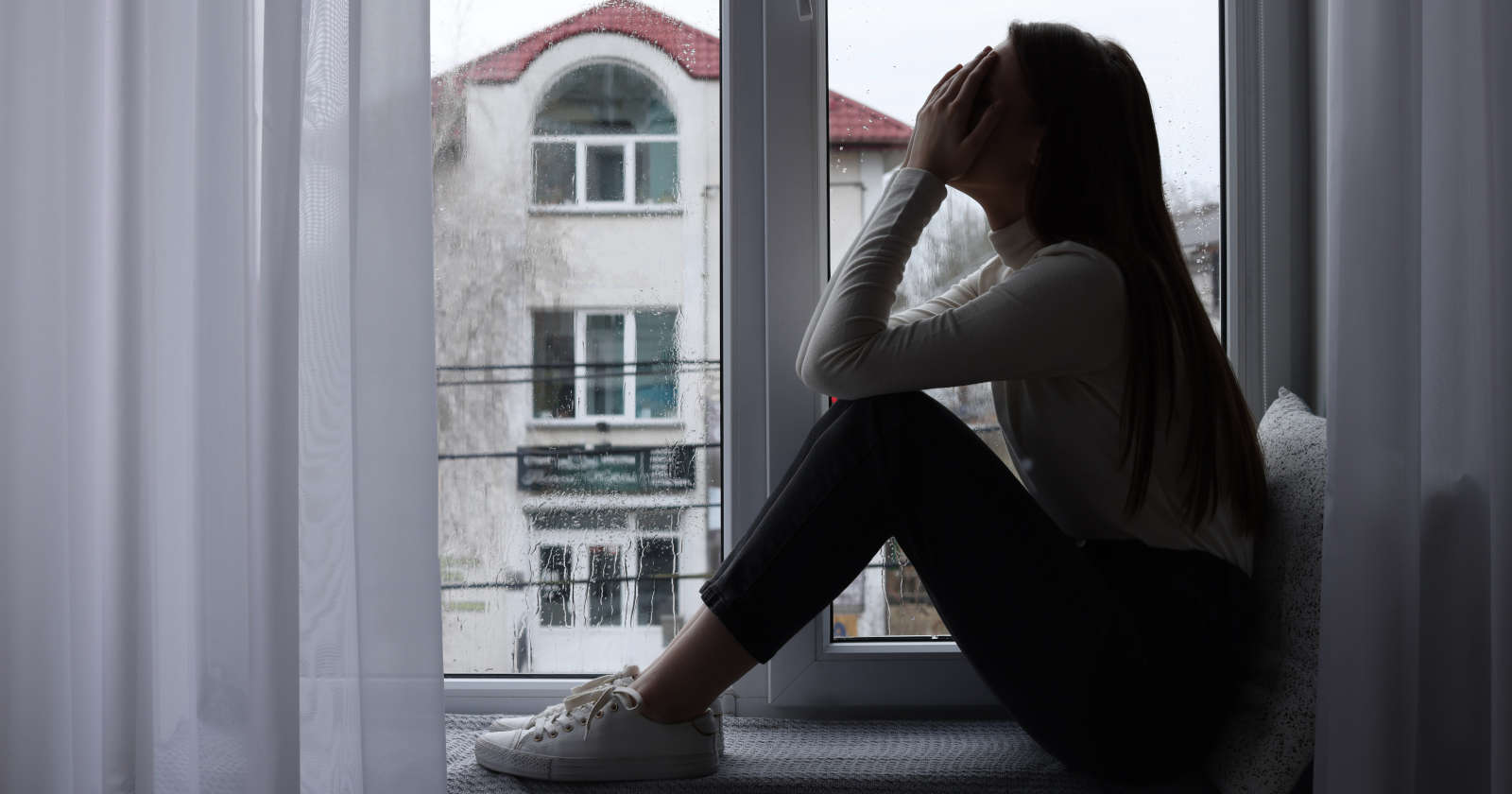 Eine verzweifelte Frau sitzt vor dem Fenster