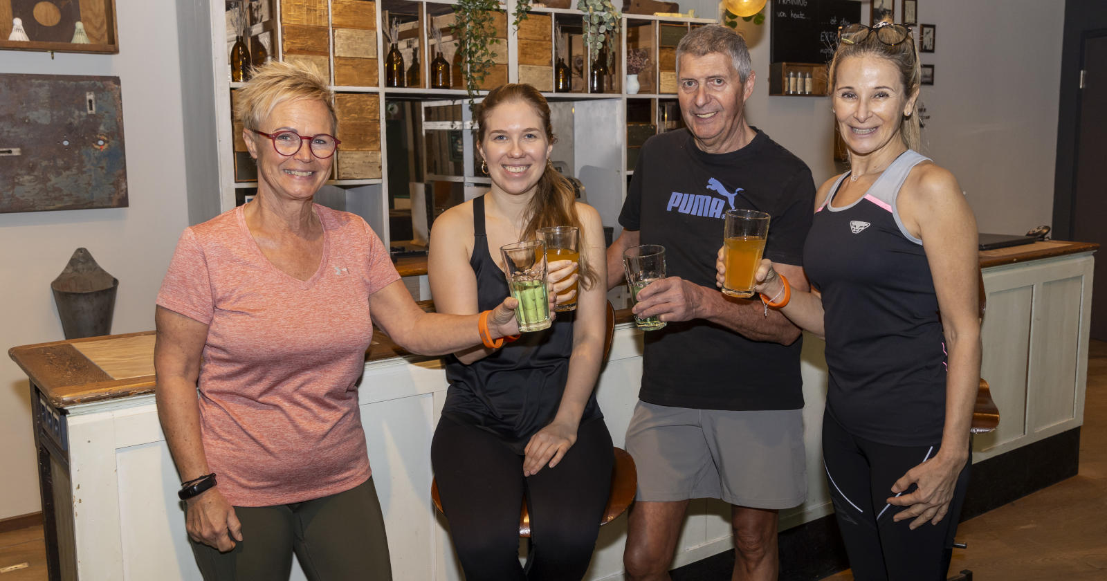 Drei Frauen und ein Mann prosten mit einem Getränk an