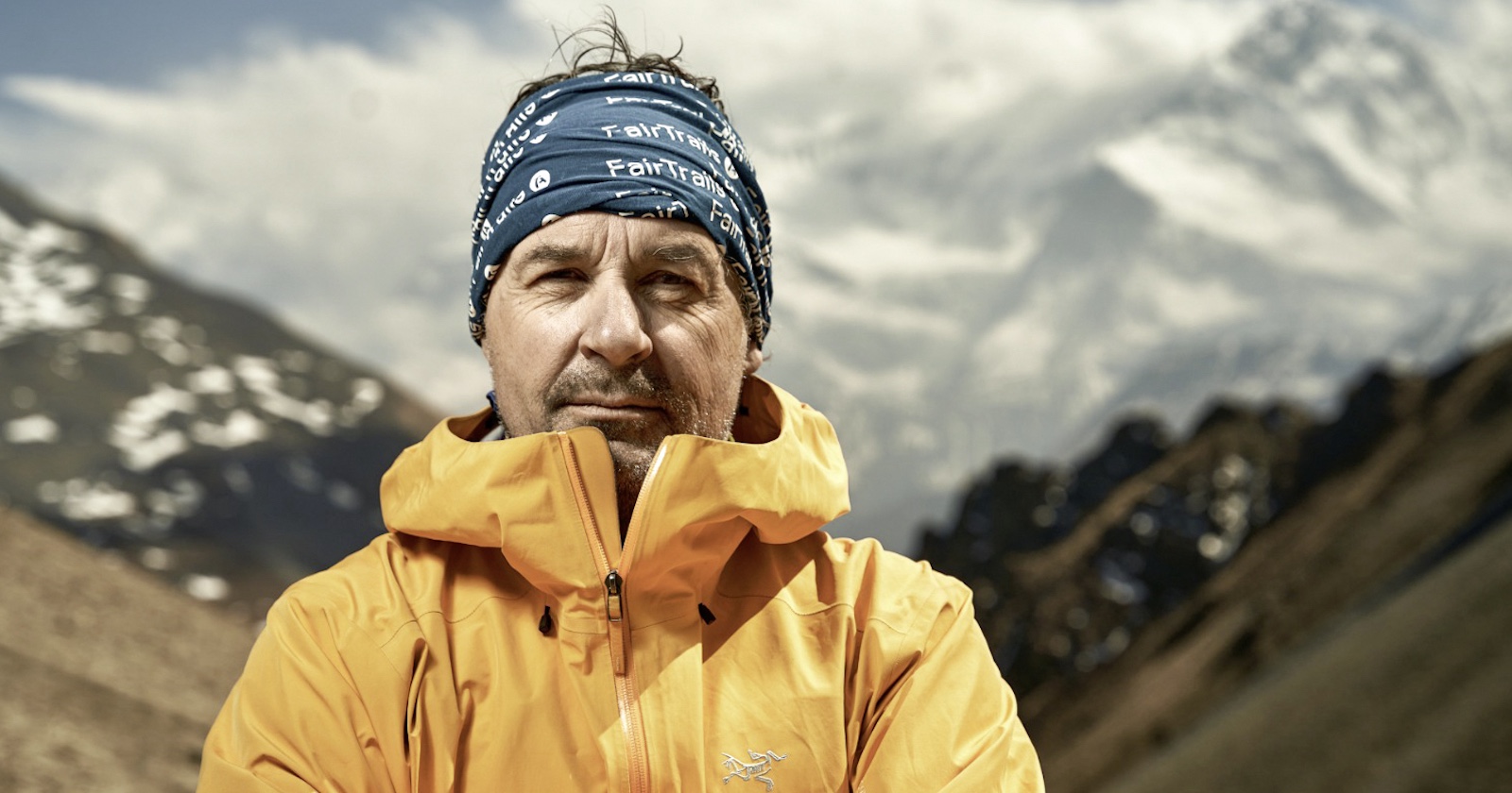 Wanderer Günter Mussnig im gelben Parker vor einer Bergkulisse