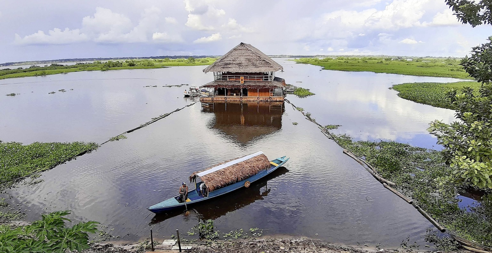 Fischerboot vor einem Pfahlbau im perunanischen Dschungel
