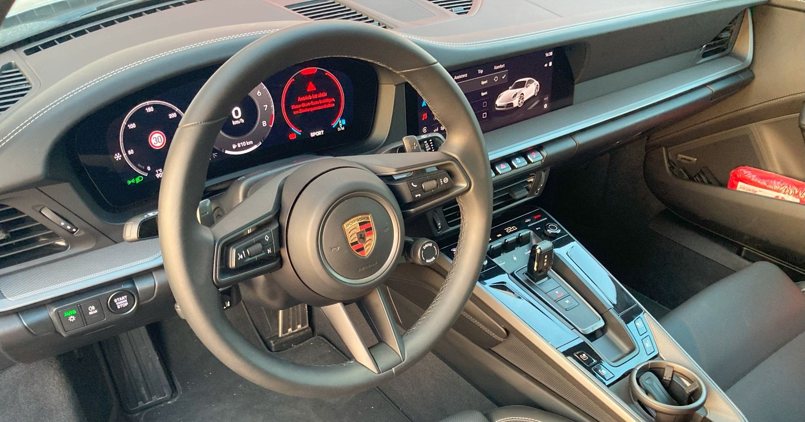 Das Innere des Porsche 911. Hellbraune Töne dominieren. Zu sehen auch das Screen für den Beifahrer.