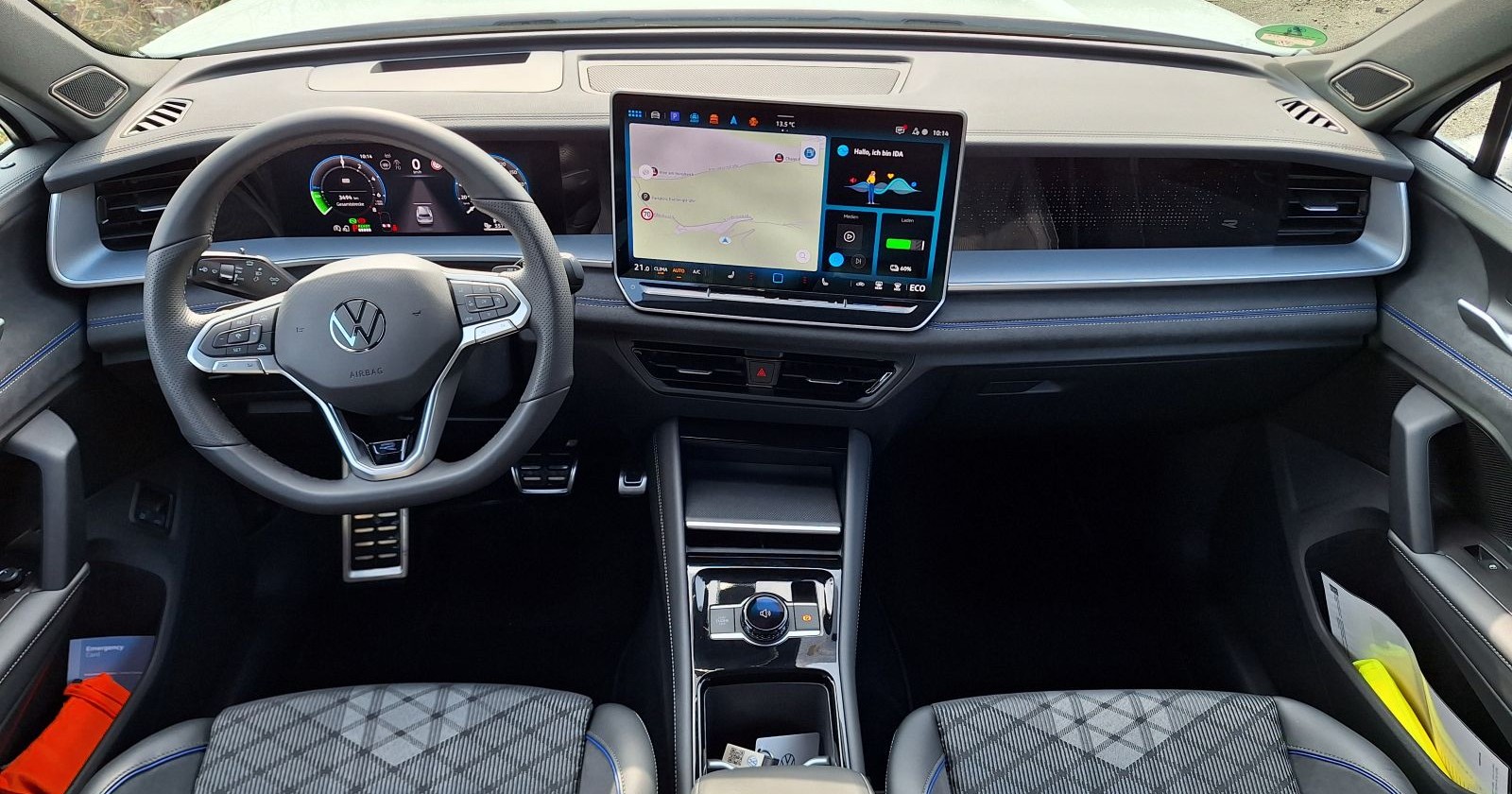 Das Cockpit des VW Tayron: Die Sitze sind mit grauem Stoff bezogen, das Lenkrad hat die selbe Farbe. Zwischen Fahrer- und Beifahrersitz ist das Display des Infosystems zu sehen.