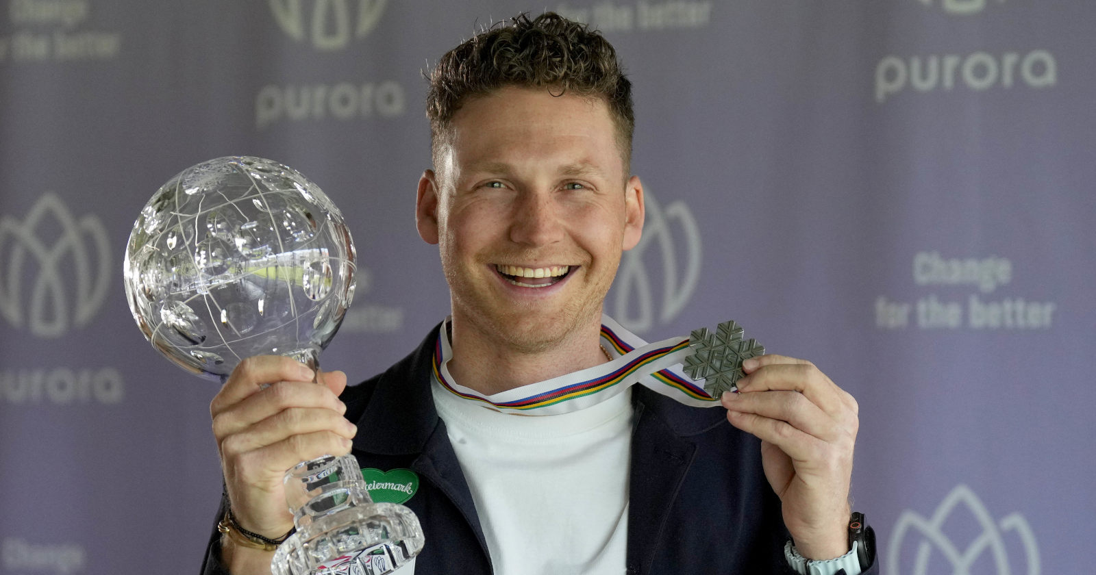 Mann hält eine Kristallkugel und eine Medaille in den Händen