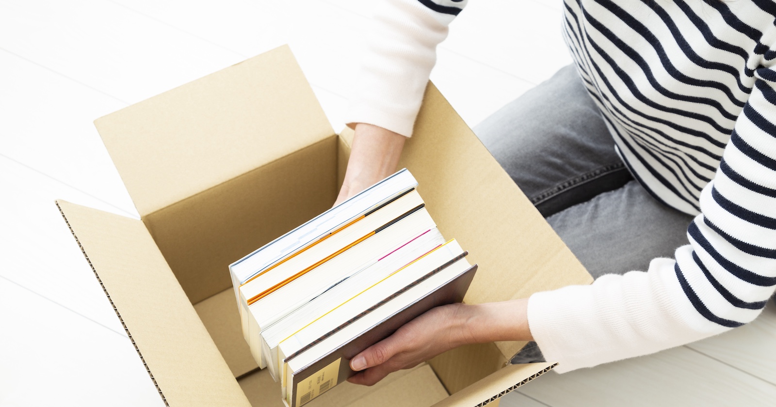 Perspektive von oben, Frau packt Bücher in Karton