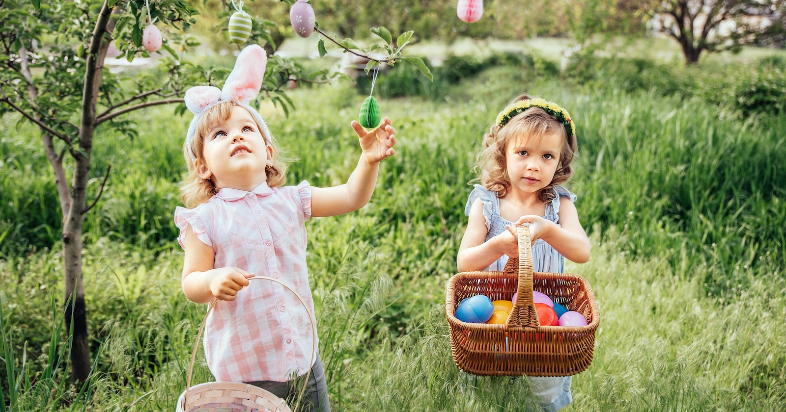 Zwei Kinder sammeln mit Körben Ostereier.