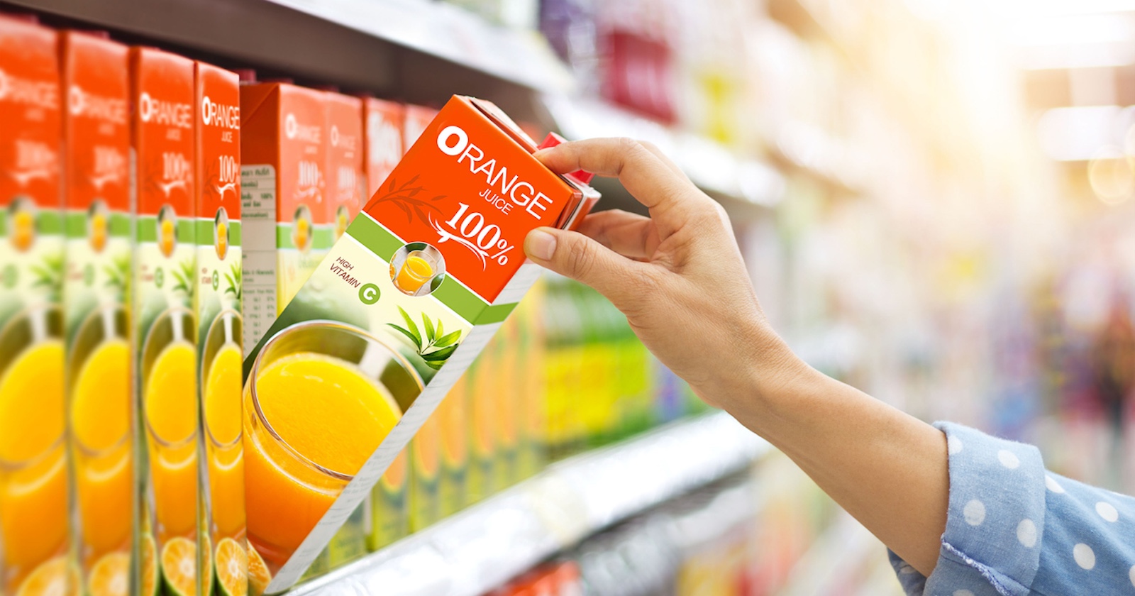 Eine Frau nimmt einen O-Saft aus dem Supermarktregal.