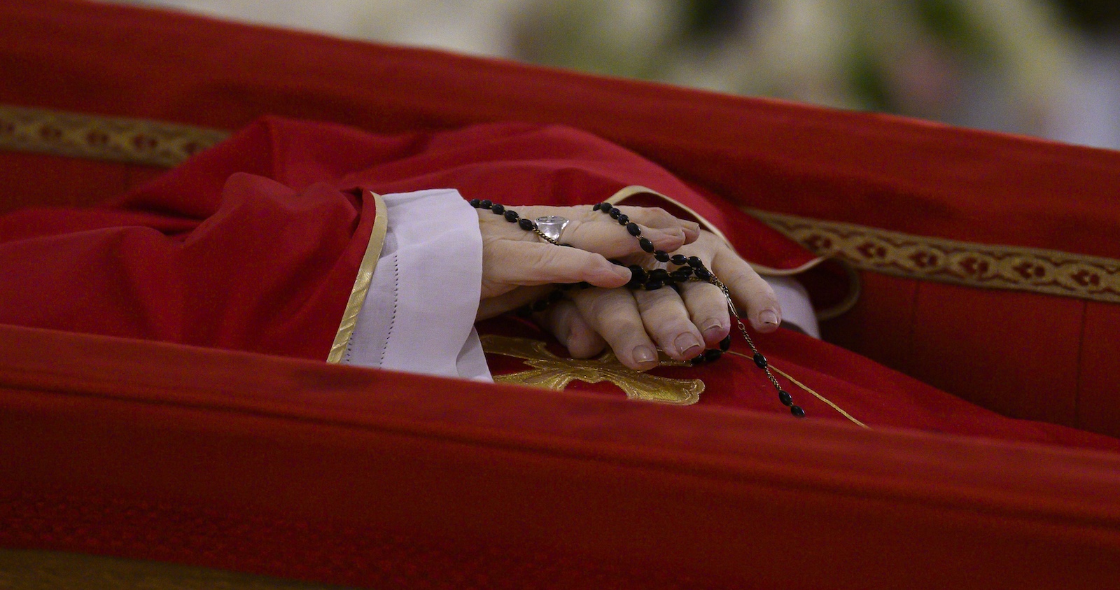 Papst Franziskus im offenen Sarg: Die gefalteten Hände halten einen schwarzen Rosenkranz, das purpurne Messgewand ist schlicht mit Goldborte verziert