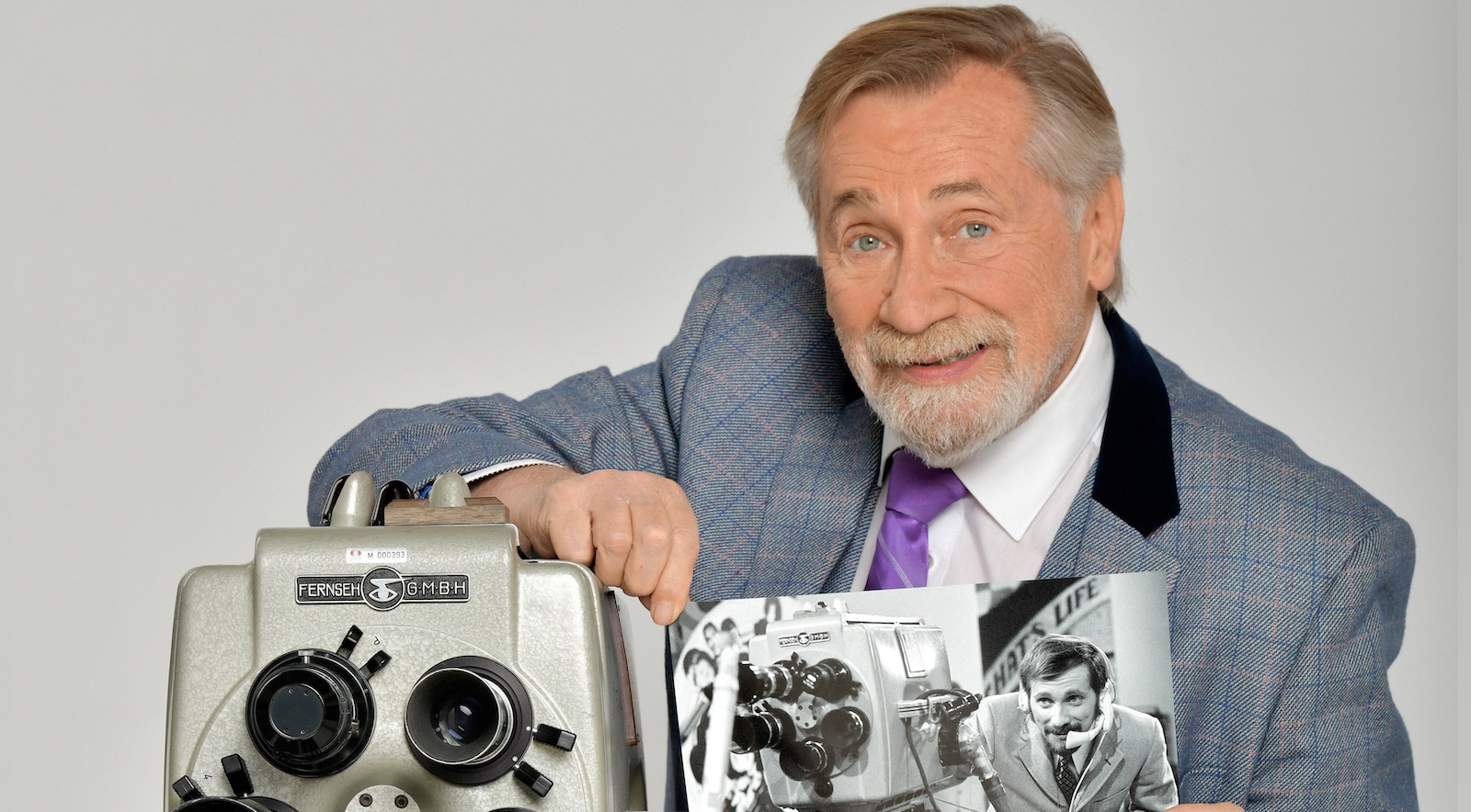 Peter Rapp zeigt stolz eine alte Aufnahme von sich mit einem historischen Fernsehgerät, das symbolisch für seine langjährige Karriere steht.