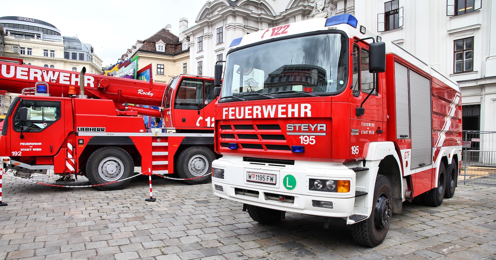 Zwei Einsatzfahrzeuge der Feuerwehr Wien stehen einsatzbereit in der Innenstadt, im Hintergrund historische Gebäude der Wiener Innenstadt.