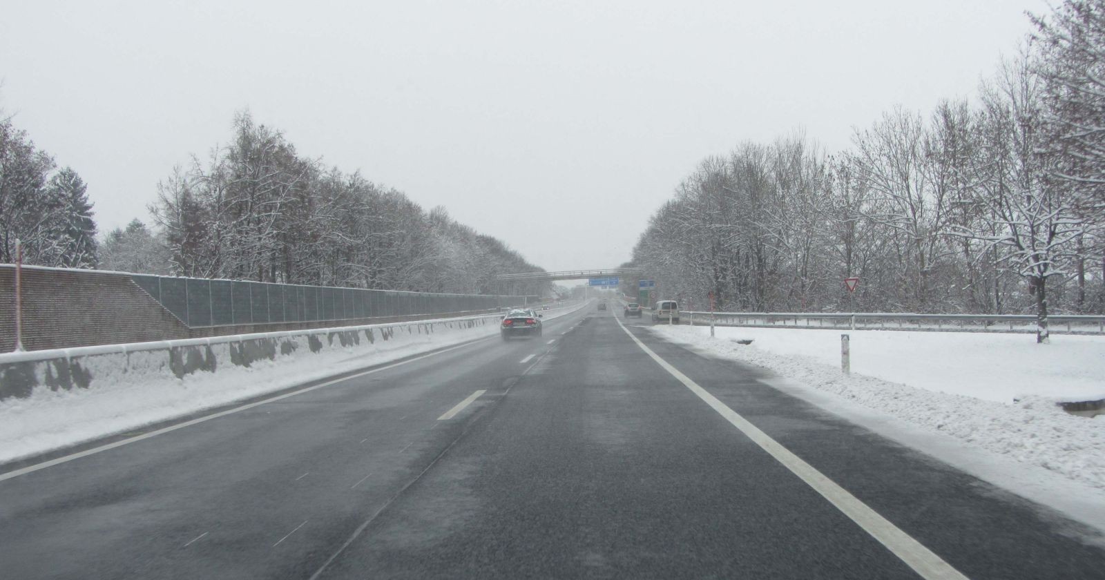 bewölkter Himmel, Auto auf einer Fahrbahn, Nebel, Schnee neben der Straße