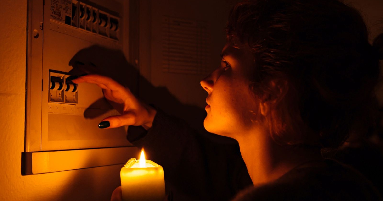 Frau mit Kerze beim Stromkasten