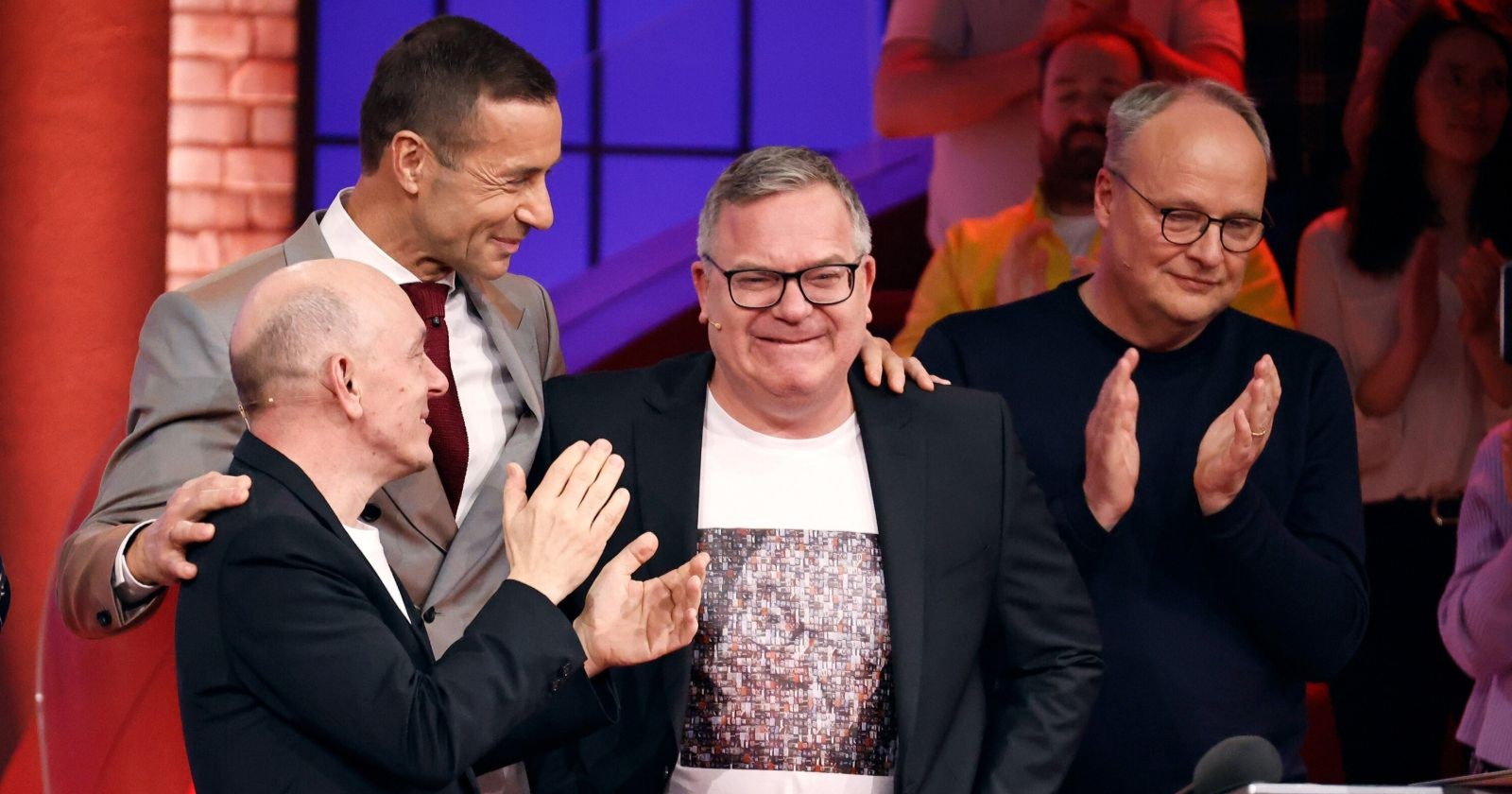 Elton lächelt gerührt bei seinem Abschied von „Wer weiß denn sowas?“, flankiert von Bernhard Hoëcker, Kai Pflaume und Oliver Welke.