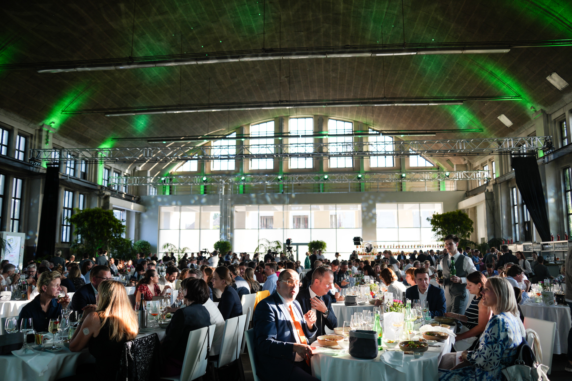 Blick in einen Veranstaltungssaal mit voll besetzten Tischen