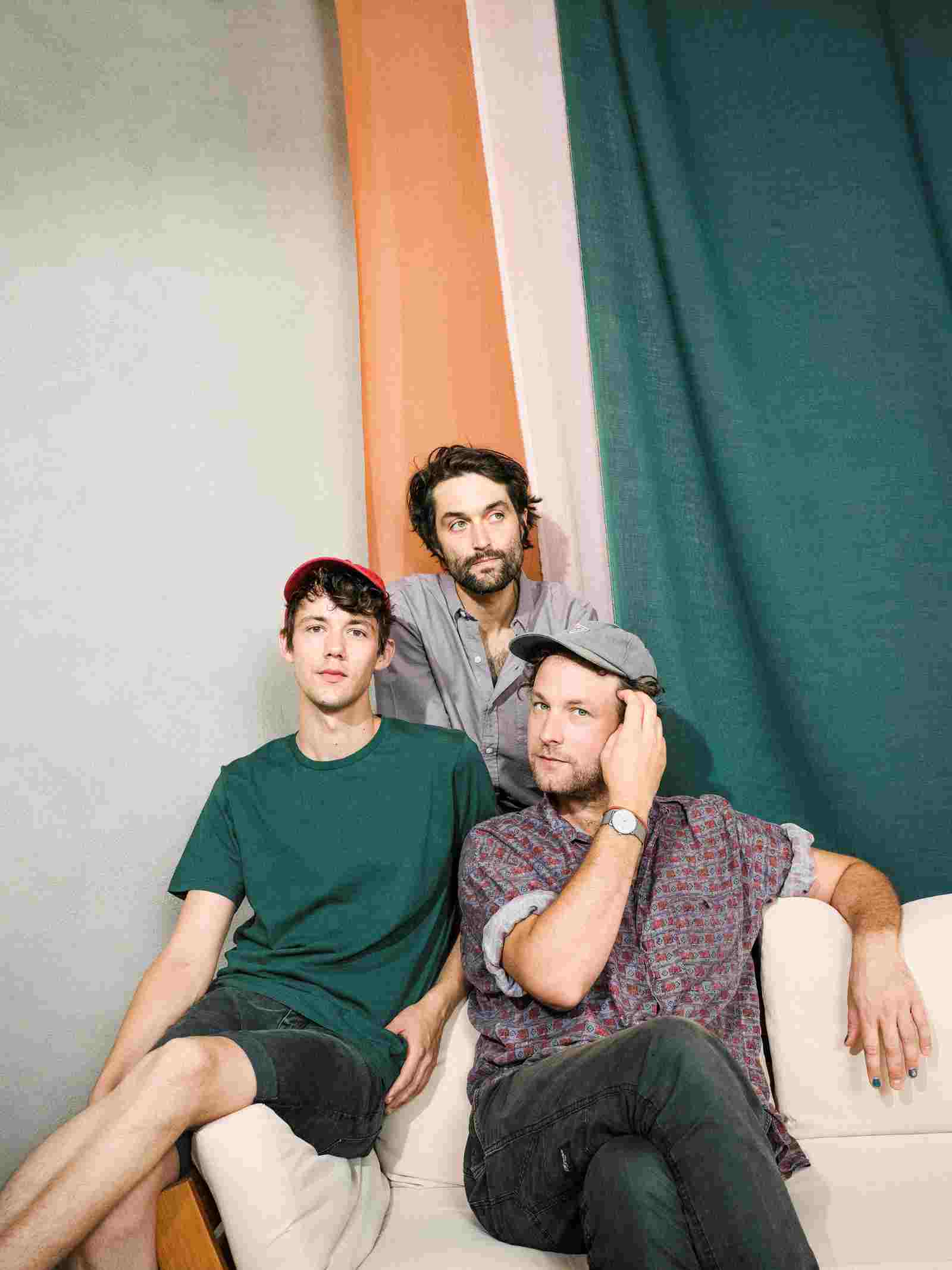 Die Band Annen May Kantereit: Drei Männer, der eine mit Baskenmütze sitzt auf der Couch, die Beine überschlagen, auf der Lehne daneben sitzt ein weiterer und dahinter der dritte.