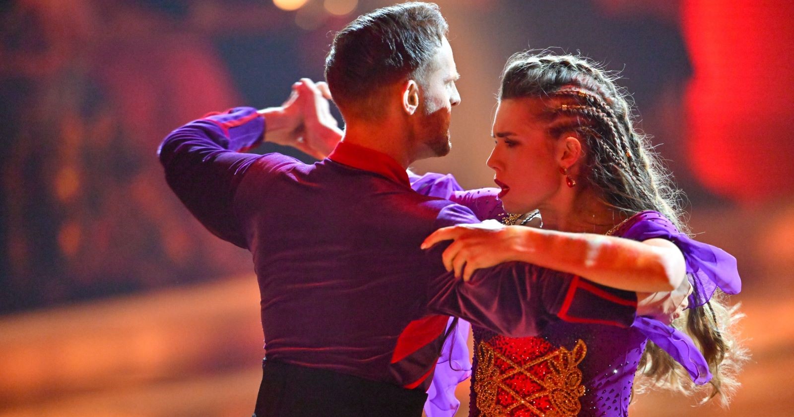 Anna Strigl und Herby Stanonik tanzen beim „Dancing Stars“-Halbfinale eng umschlungen einen intensiven Paso Doble, beide in violett-roten Kostümen, mit konzentrierten Gesichtern und dramatischer Körperspannung.