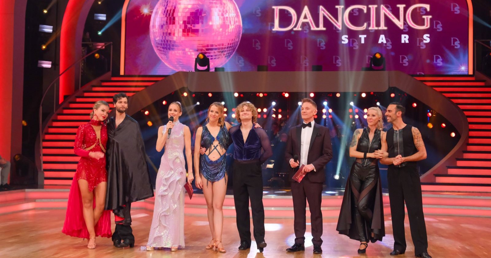 Finale von Dancing Stars 2025 mit Aaron Karl und Katya Mizera, Paulus Bohl und Catharina Malek, Simone Lugner und Danilo Campisi sowie den Moderatoren Mirjam Weichselbraun und Andi Knoll auf der Bühne, vor dem Logo der Show.