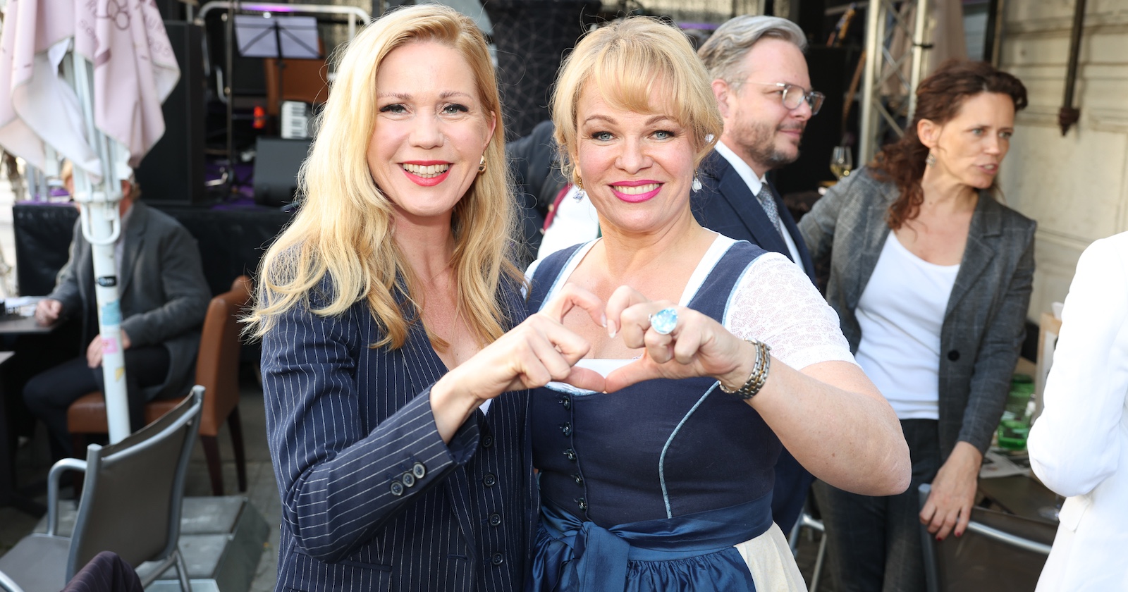 Zwei blonde Frauen formen mit ihren Händen ein Herz