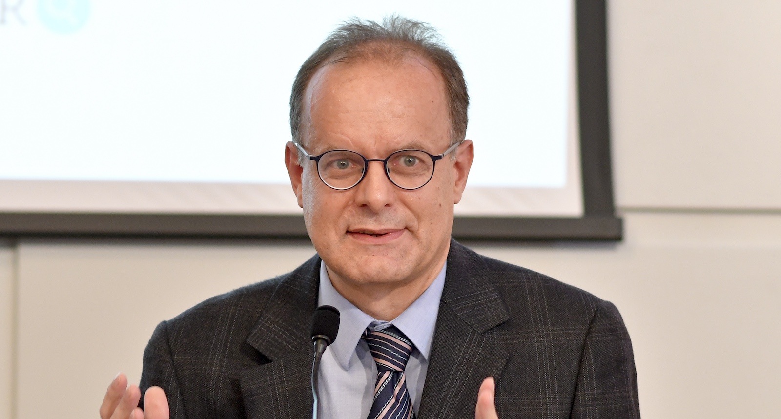 Hubert Sickinger spricht bei einer Veranstaltung, trägt Anzug, Krawatte und Brille, im Hintergrund eine Leinwand – er war Politikwissenschafter und Jurist.