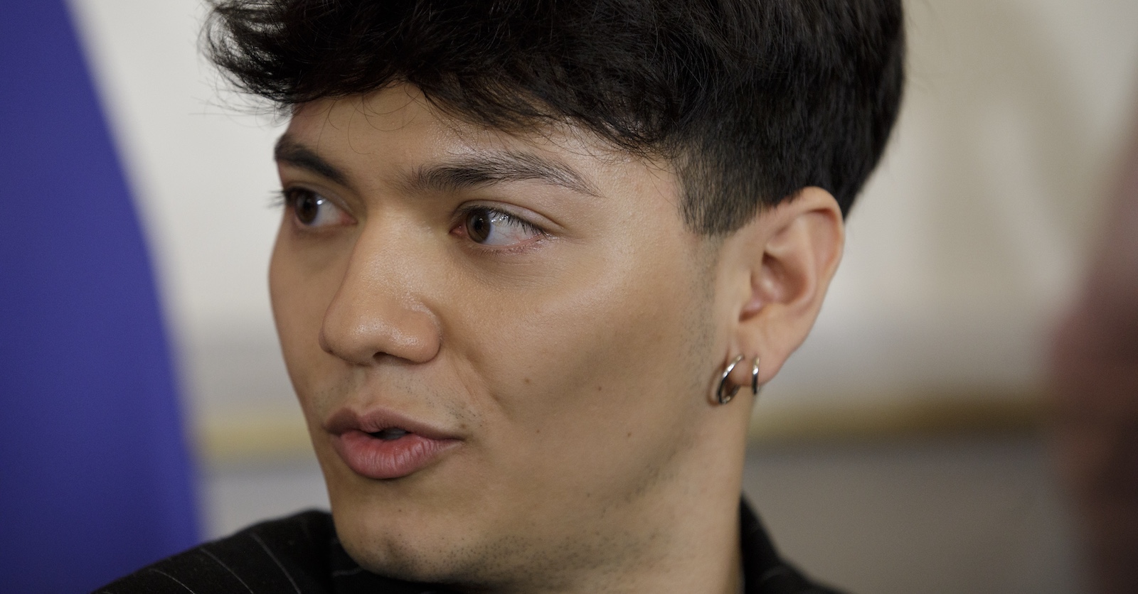 Nahaufnahme von ESC-Gewinner JJ mit ernster Miene, Blick zur Seite gerichtet, sichtbar mit Ohrringen – aufgenommen während eines Interviews oder Pressetermins.