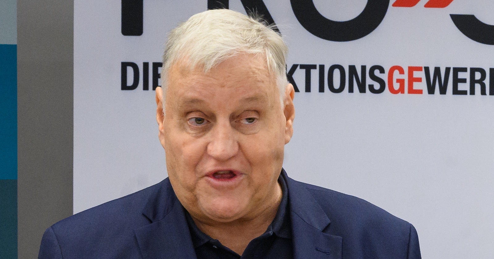 Porträt von Karl Dürtscher bei einer Rede vor dem Logo der Produktionsgewerkschaft PRO-GE. Der verstorbene Gewerkschafter war Bundesgeschäftsführer der GPA.