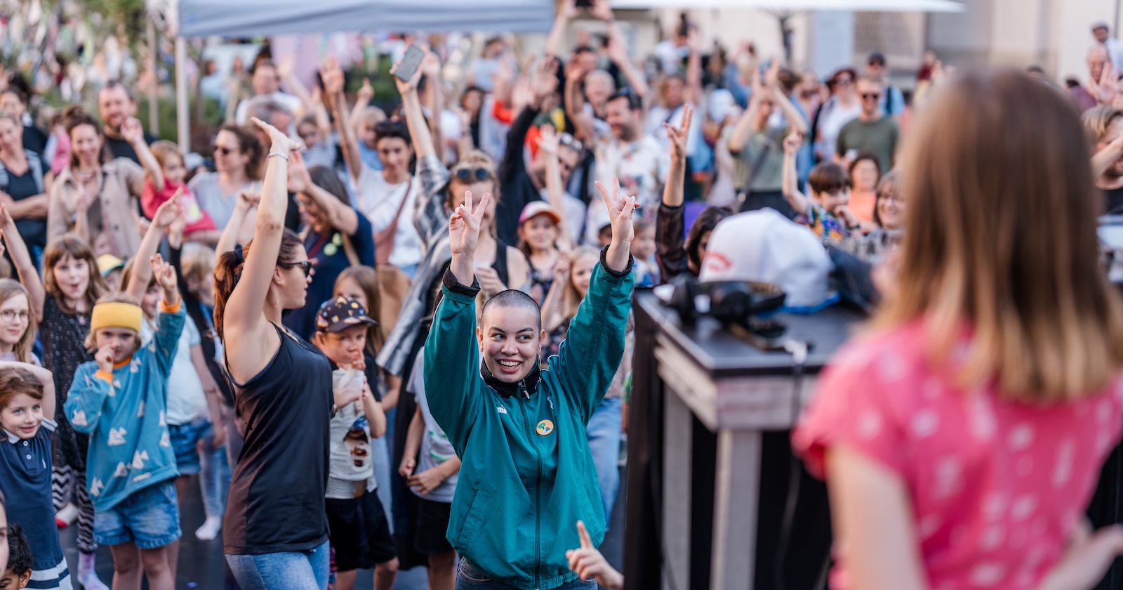 Fröhliche Menschen reißen vor einer Bühne im Museumsquartier die Hände in die Höhe