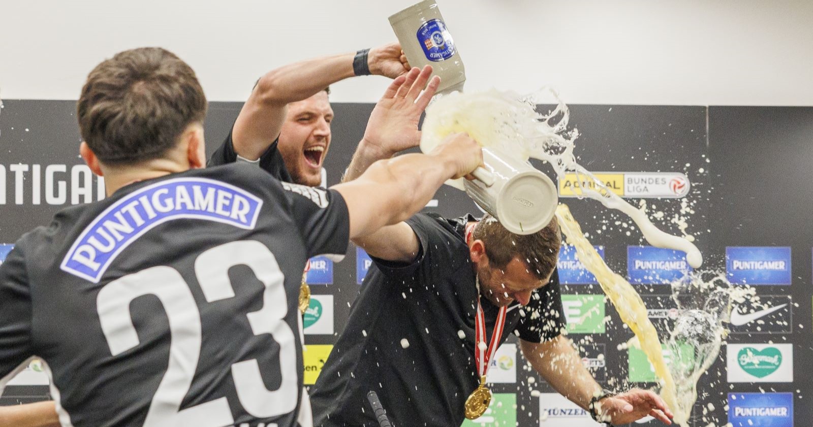 Zwei Spieler von Sturm Graz überschütten ihren Trainer nach dem Meistertitel jubelnd mit Bier.