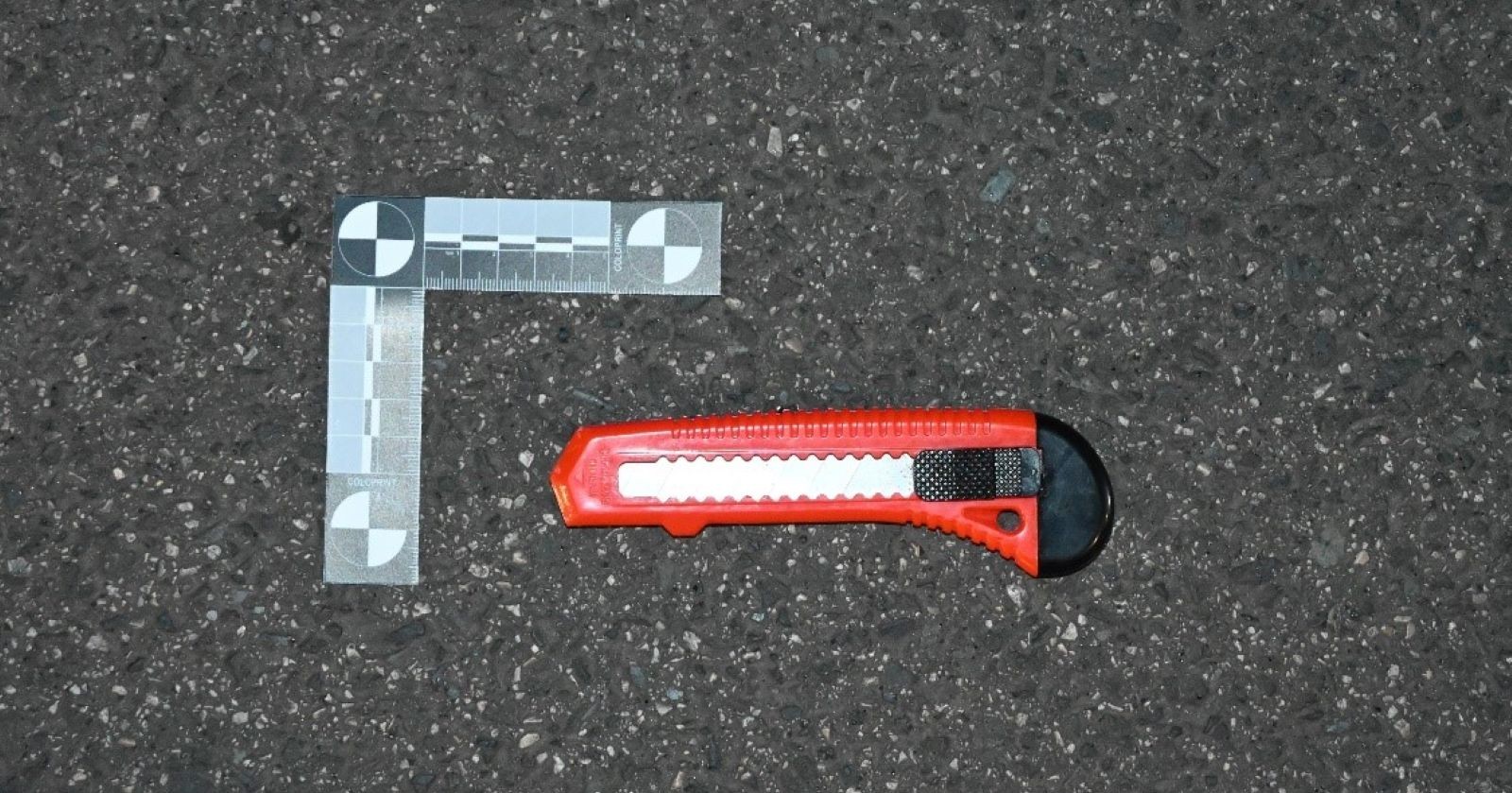 Rotes Teppichmesser liegt am Boden mit grauem Messband links daneben