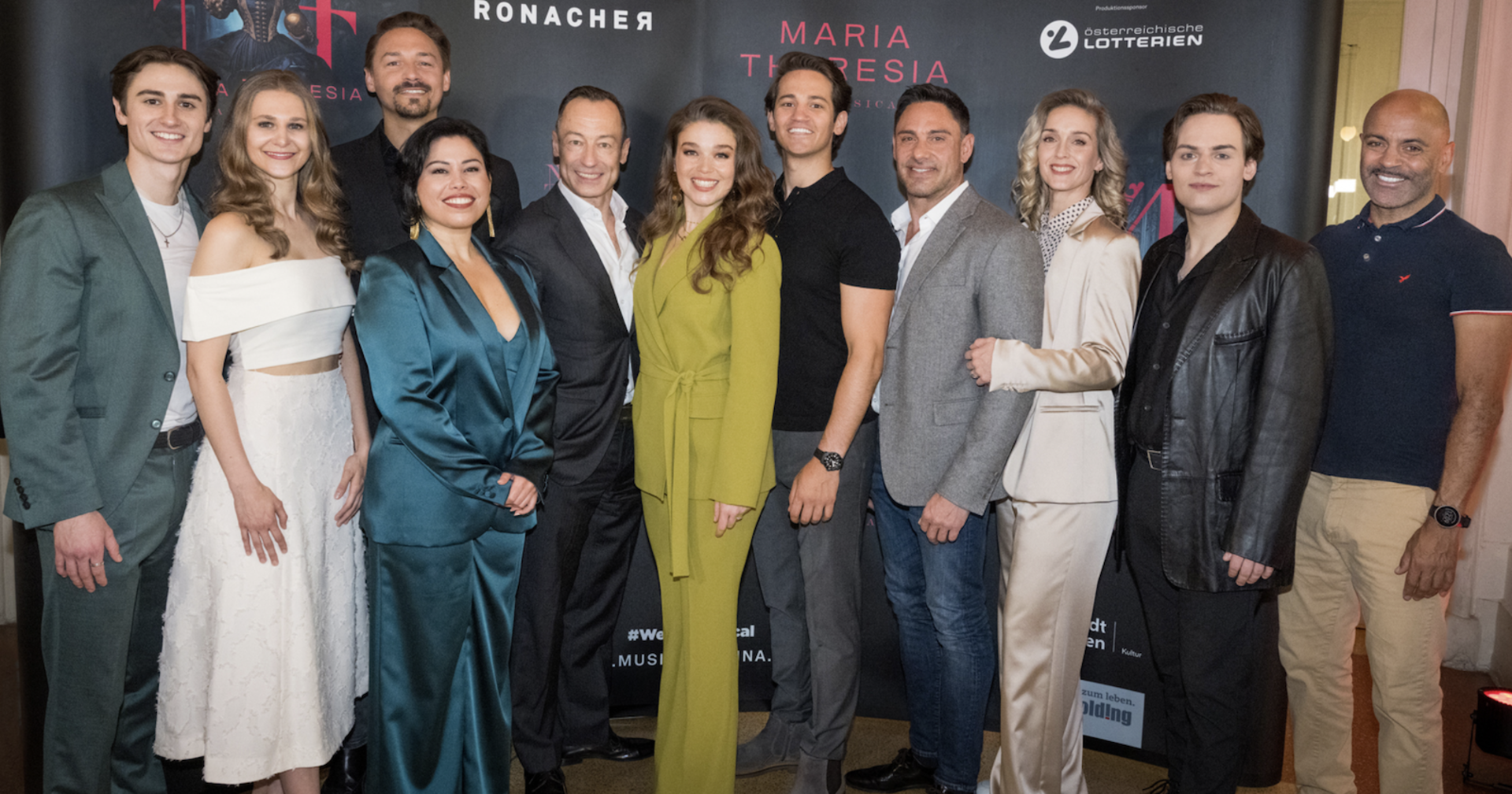 Musical-Produzenten und Musical-Darsteller stehen vor einer Plakatwand im Ronacher