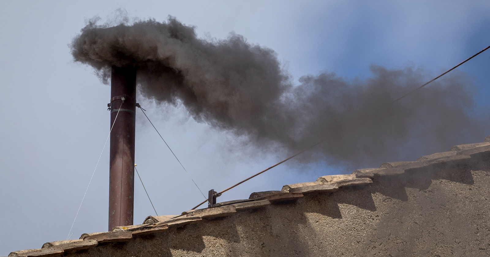 „Dichter schwarzer Rauch steigt aus einem Metallkamin auf dem Dach der Sixtinischen Kapelle in den Himmel – Zeichen für eine erfolglose Papstwahl.
