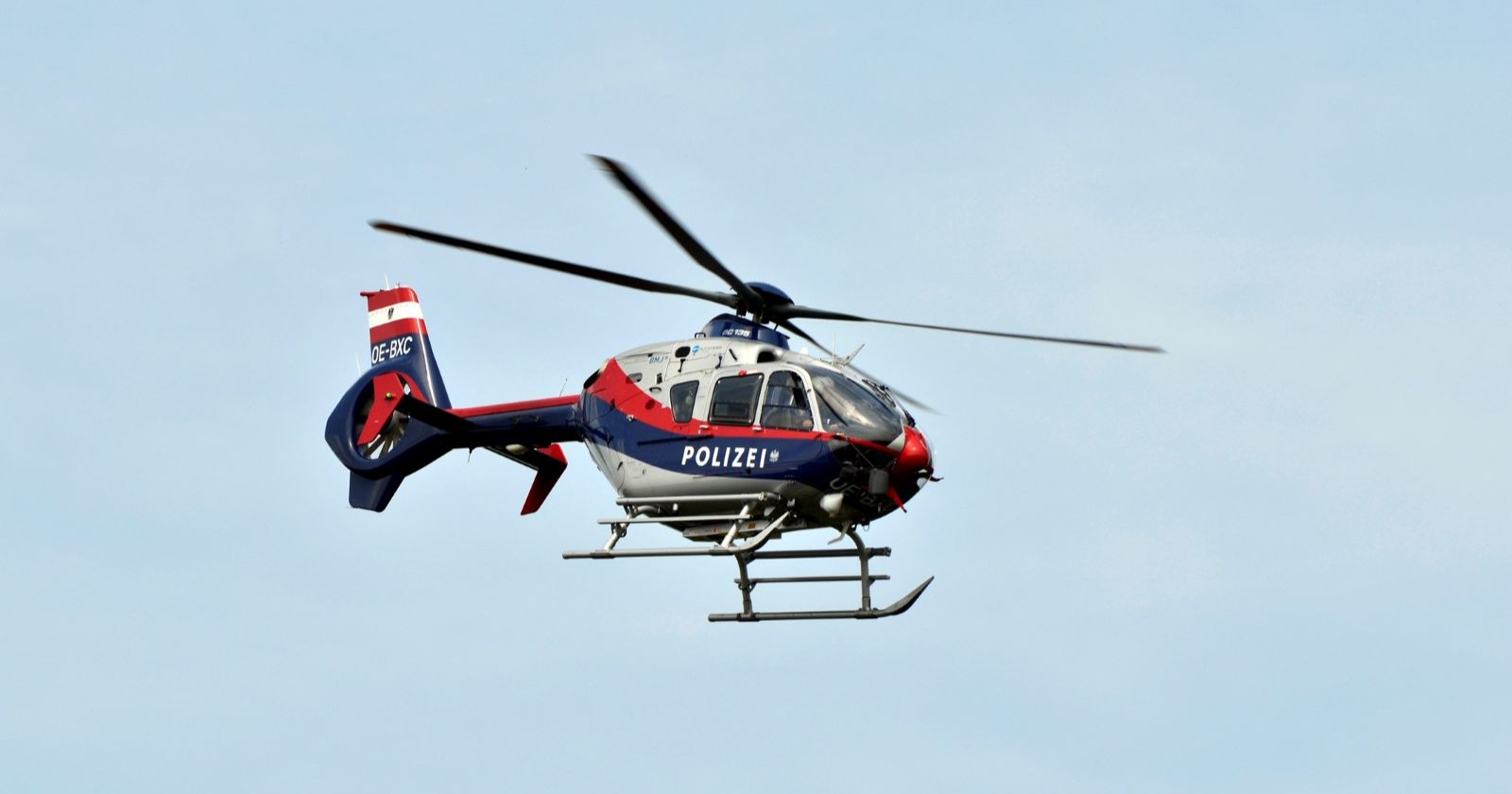 Polizeihubschrauber der österreichischen Flugpolizei vom Typ EC135 in der Luft vor blauem Himmel