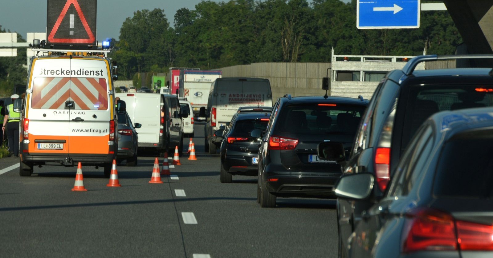 Autos stehen im Stau, Streckendienst der ASFINAG mit Verkehrsschild mit Rufzeichen links am Fahrbahnrand