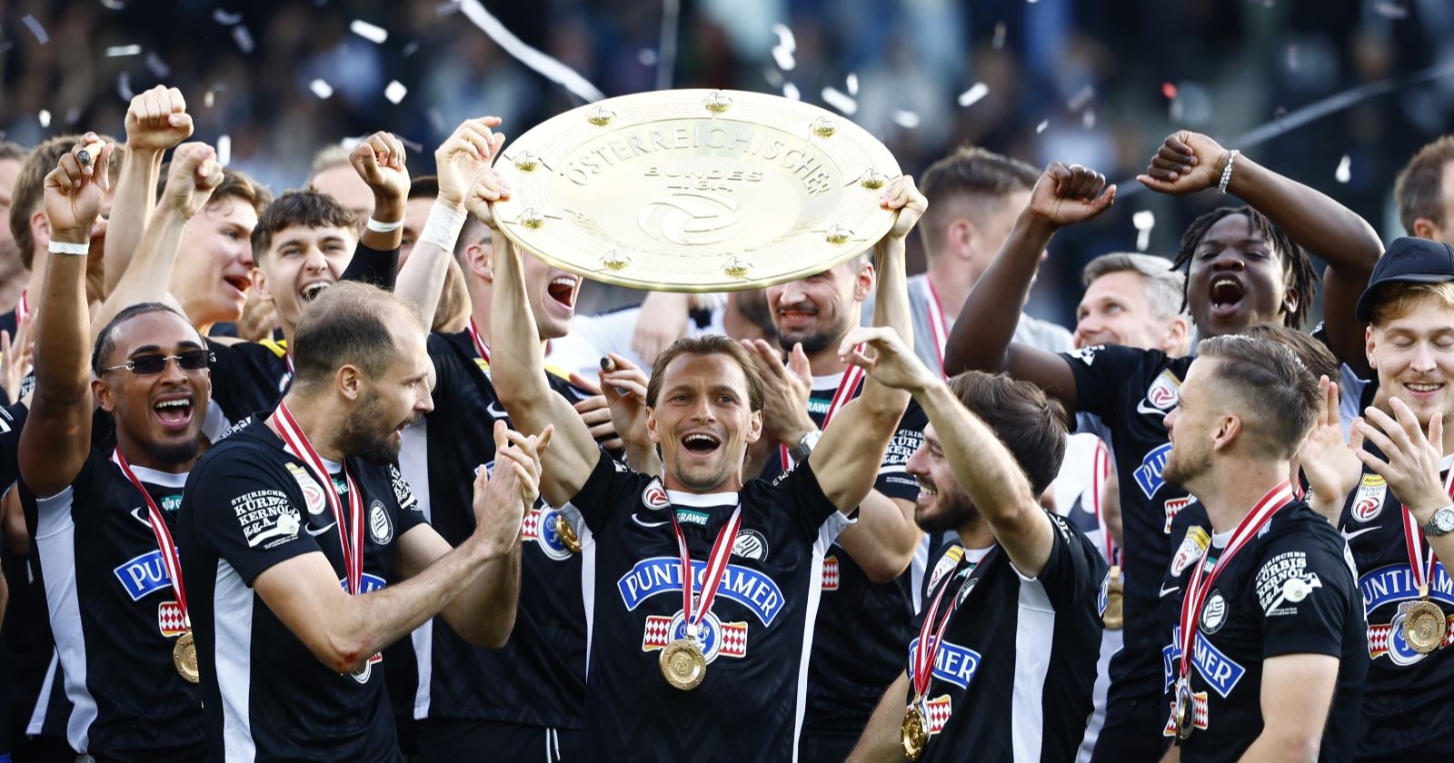 Die Mannschaft von Sk Sturm Graz feiert jubelnd und hält den Meisterteller in die Höhe