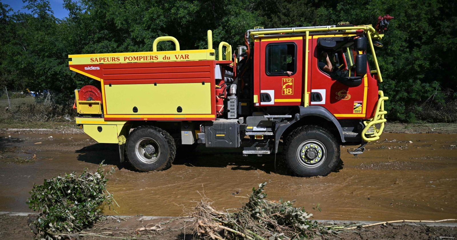 Unwetter in Südfrankreich: Ein Feuerwehrfahrzeug steht in einer überschwemmten Gegend, davor abgebrochene Baumteile