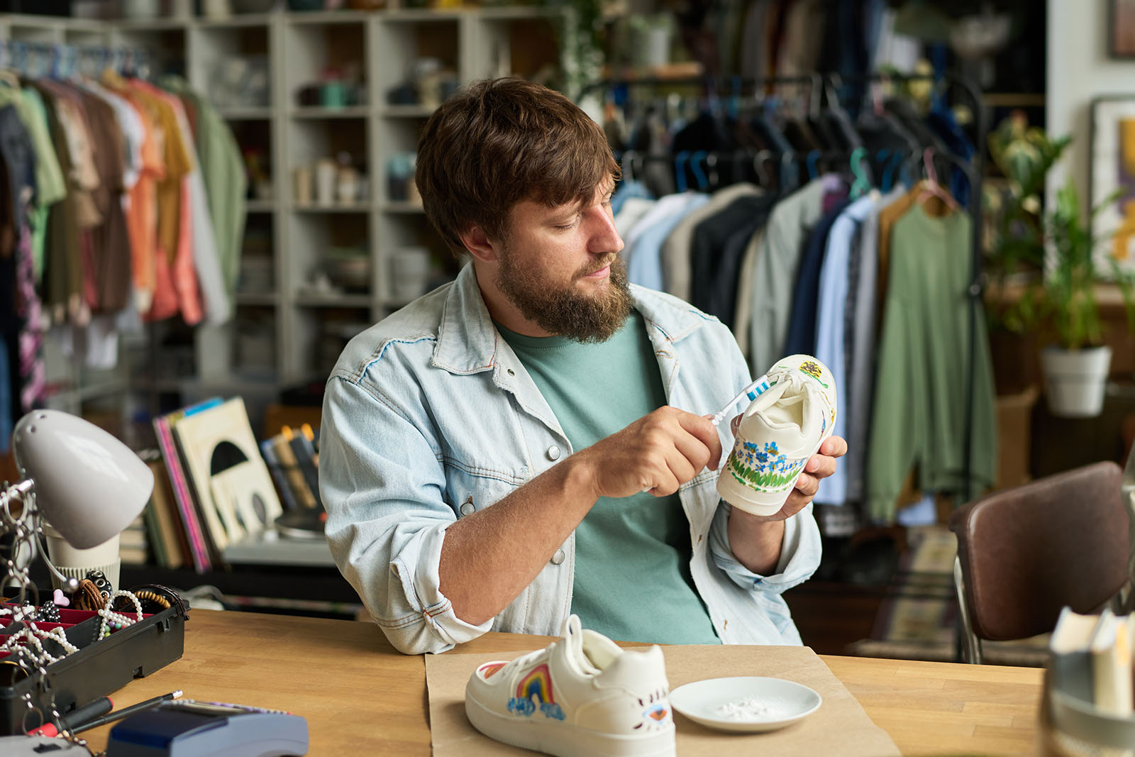 Mann reinigt weiße Sneaker mit einer Zahnbürste | Credit: iStock.com/shironosov