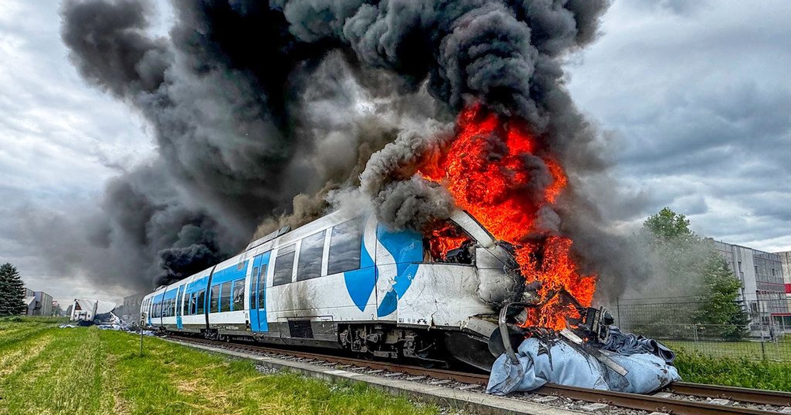 Ein brennender weiß-blauer S-Bahn-Zug mit meterhohen Flammen und dichten schwarzen Rauchwolken, nach einem Zusammenstoß mit einem Lkw auf einem Bahnübergang in der Oststeiermark.