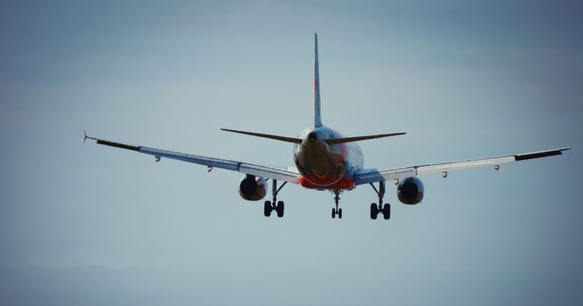 Ein Passagierflugzeug im Landeanflug, aufgenommen von hinten gegen den Himmel – symbolisch für kommende Änderungen bei Flughafenkontrollen.