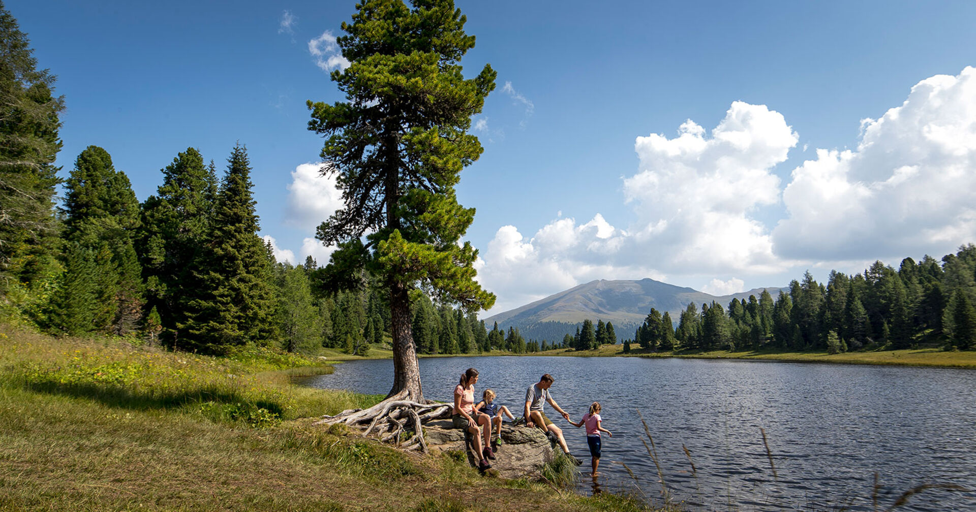 Familie am Ufer eines Waldsees | Credit: Holzwelt Murau/Tom Lamm