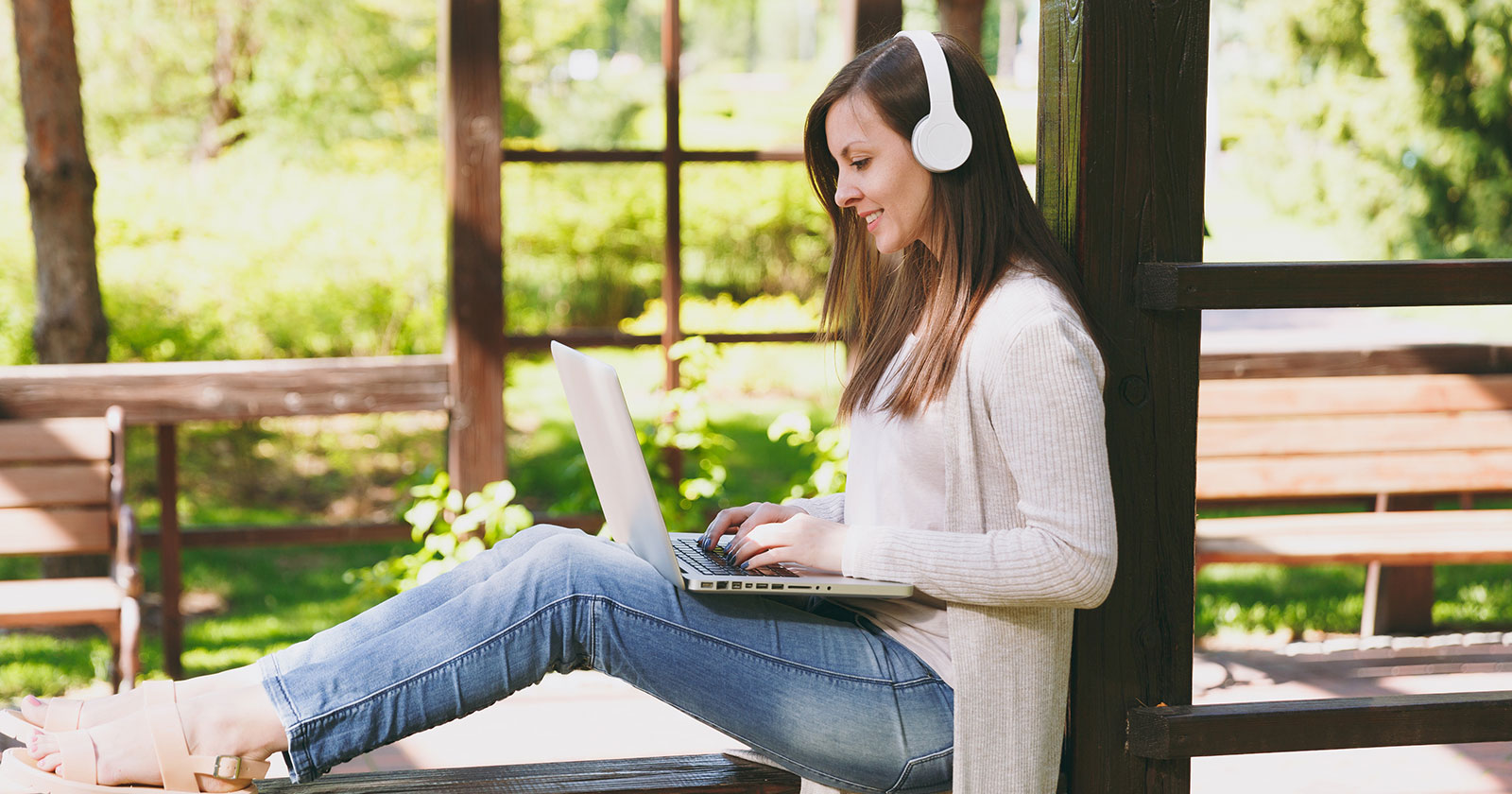 Junge Frau mit Notebook am Schoß im Grünen | Credit: iStock.com/ViDi Studio